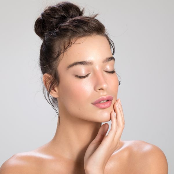 A stunning woman with radiant, silky-smooth skin showcases the benefits of a Dermaplane Facial at Admire Aesthetics in Medford, OR.