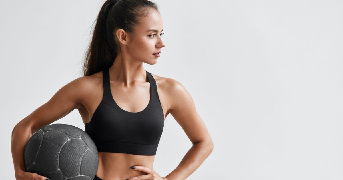 Blog-Admire Aesthetics-TruSculpt Flex vs. Regular Workouts What It Can and Cannot Replace Woman in black workout attire holding a medicine ball.